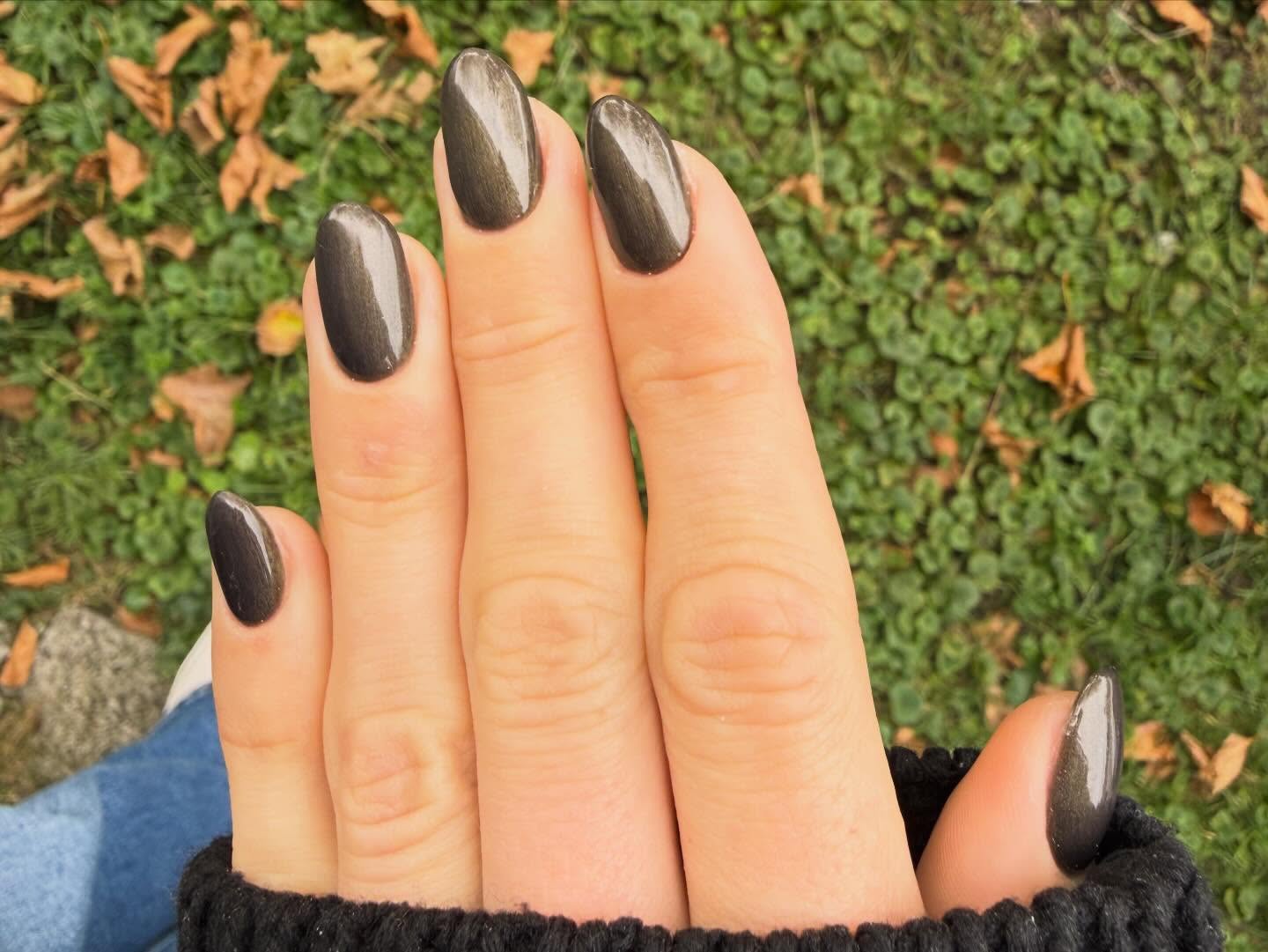 Antraciet cat-eye gellak op amandelvormige nagels, hand op het gras